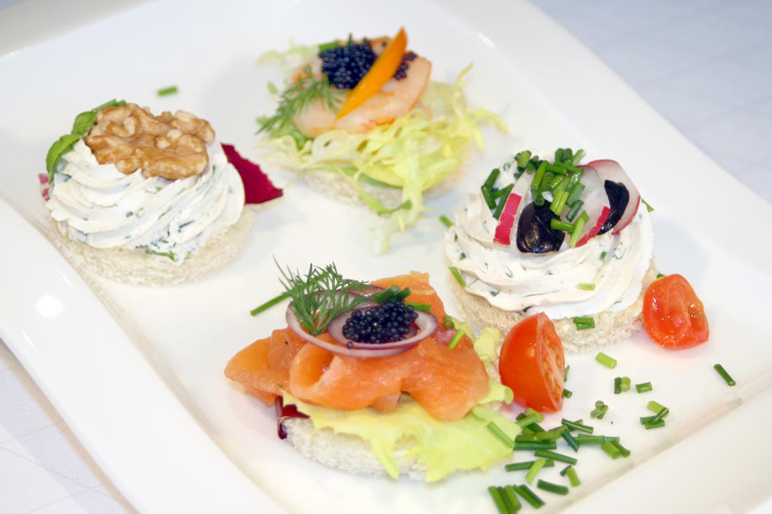 Canapés-Quartett - hausgebeizter Lachs und Caviar, knackige Garnele auf Salatbett, Ziegenkäsecreme und Walnuss, Frühlings-Olivenpaste